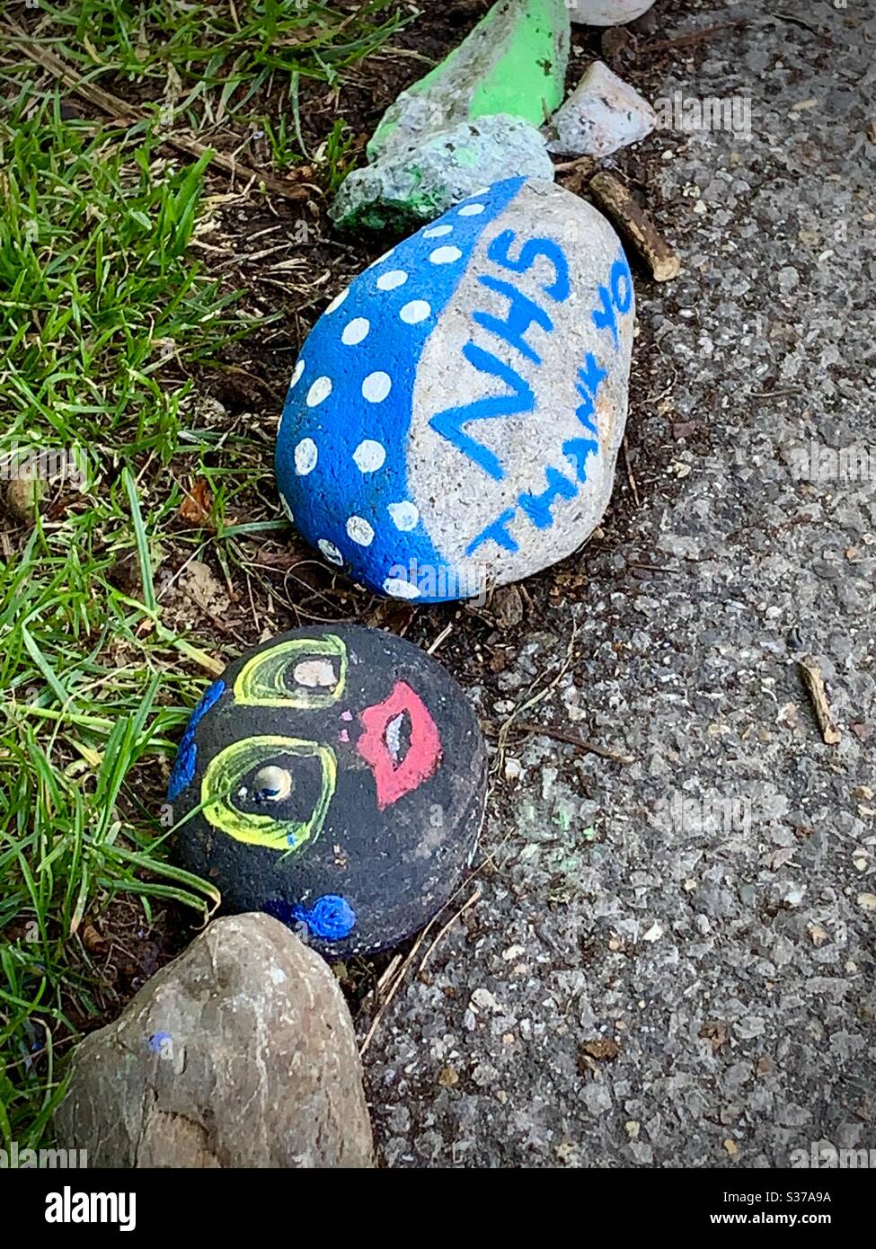 Painted pebbles lining a footpath in Bushy Park. Painted by local children from Hampton Hill the pebbles thank the National Health Service for its support during the Covid-19 pandemic lockdown in 2020 - Smartphone Captured Stock Image