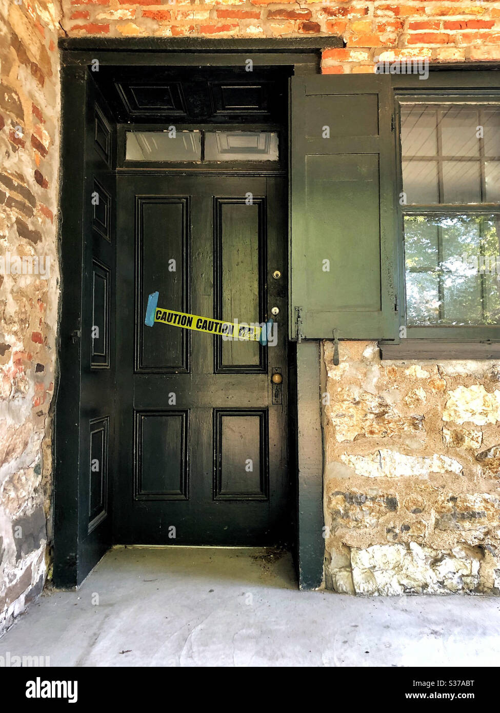 Door to old stone house with ‘Caution’ construction or warning tape