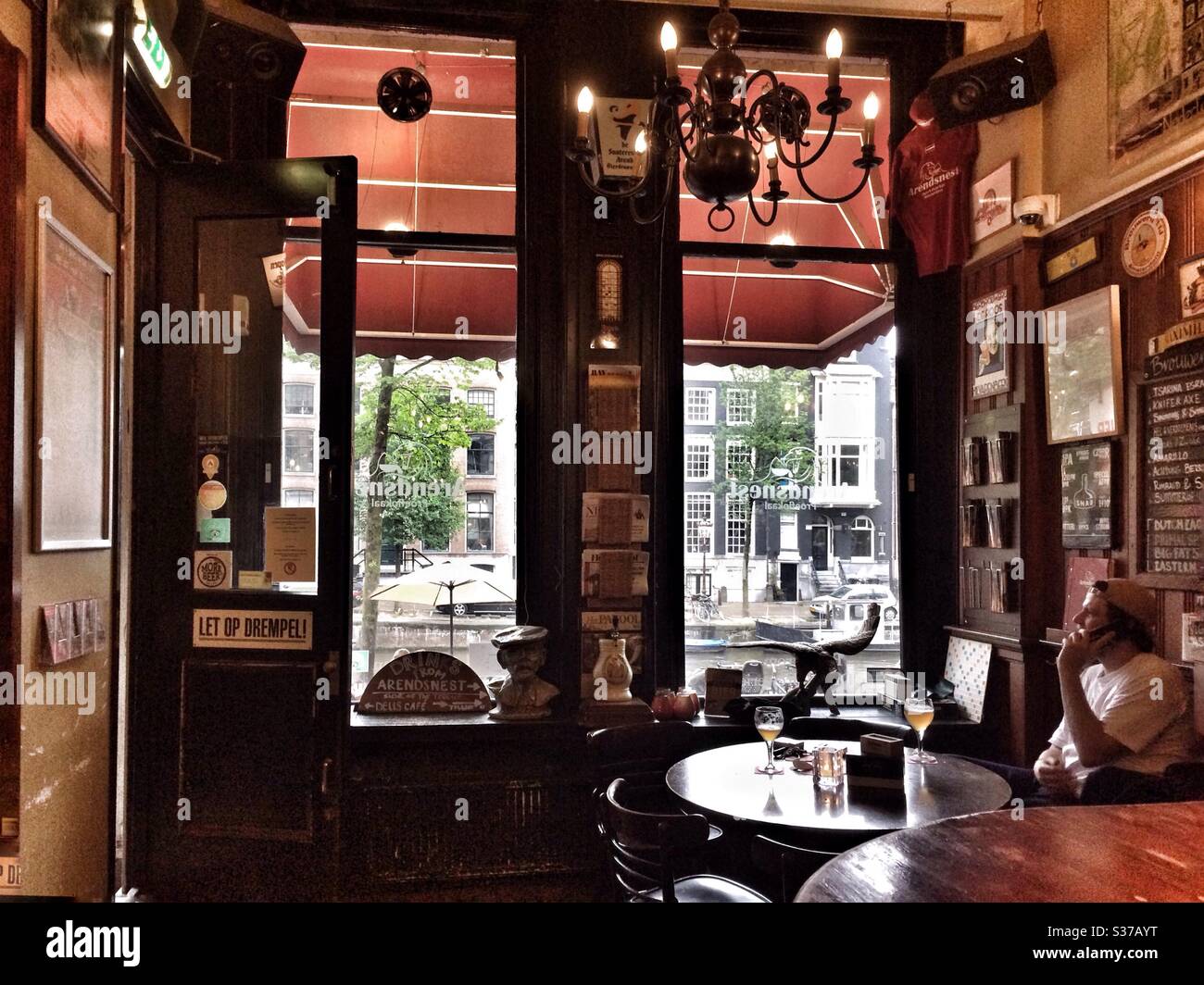 A man sits in a bar in old Amsterdam with a view to the street outside - Smartphone Captured Stock Image