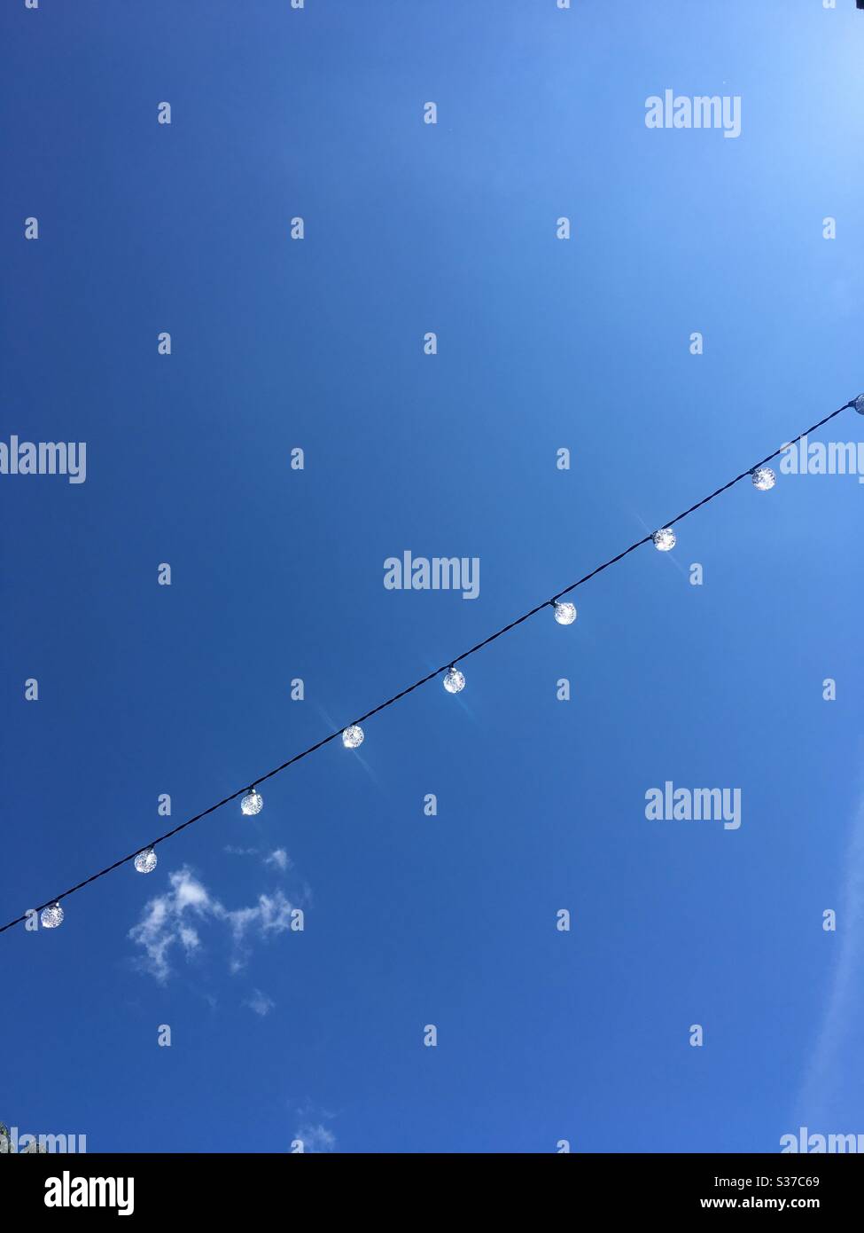 Blue sky with string of solar lights Stock Photo