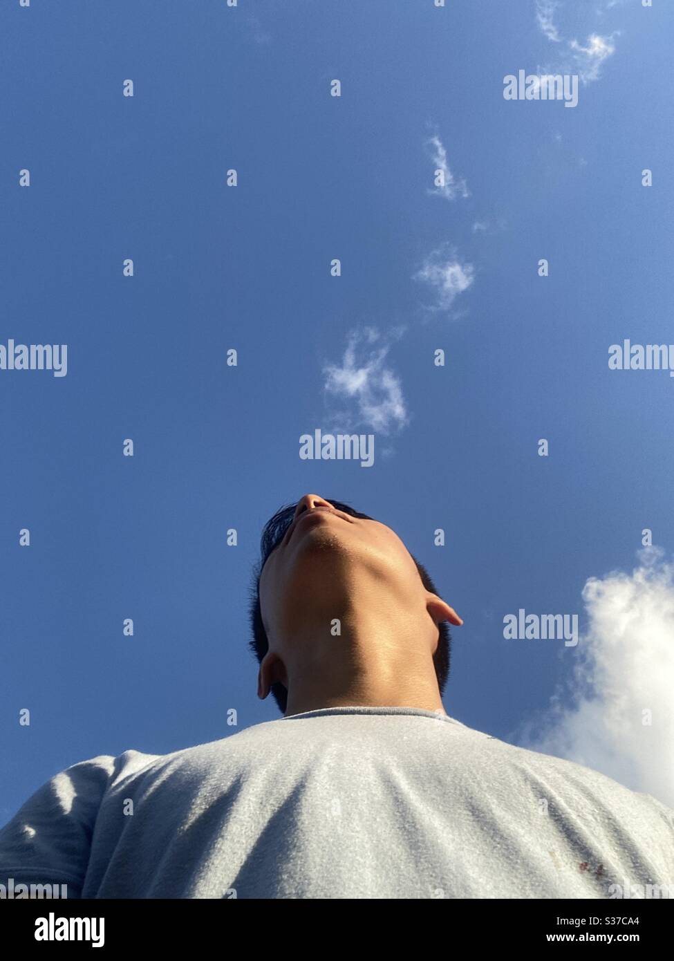 Joven con un cielo despejado demostrando interés de estar solo en un espacio confuso Stock Photo