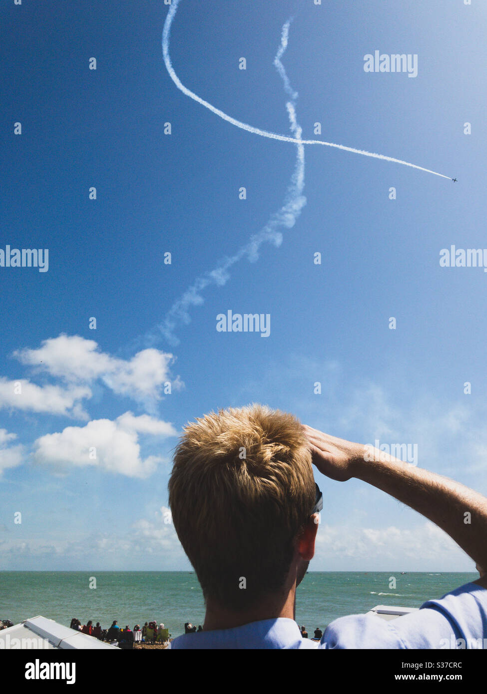 A spectator watching a stunt plane perform tricks in the sky during the Eastbourne Airshow, Sussex, UK. Stock Photo