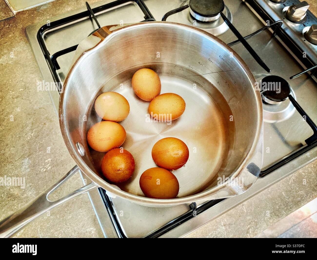 Closeup view of free range organic farm eggs in a pan of boiling water. Preparing hard boiled eggs on the stovetop. Gently simmering over gas stove. - Smartphone Captured Stock Image