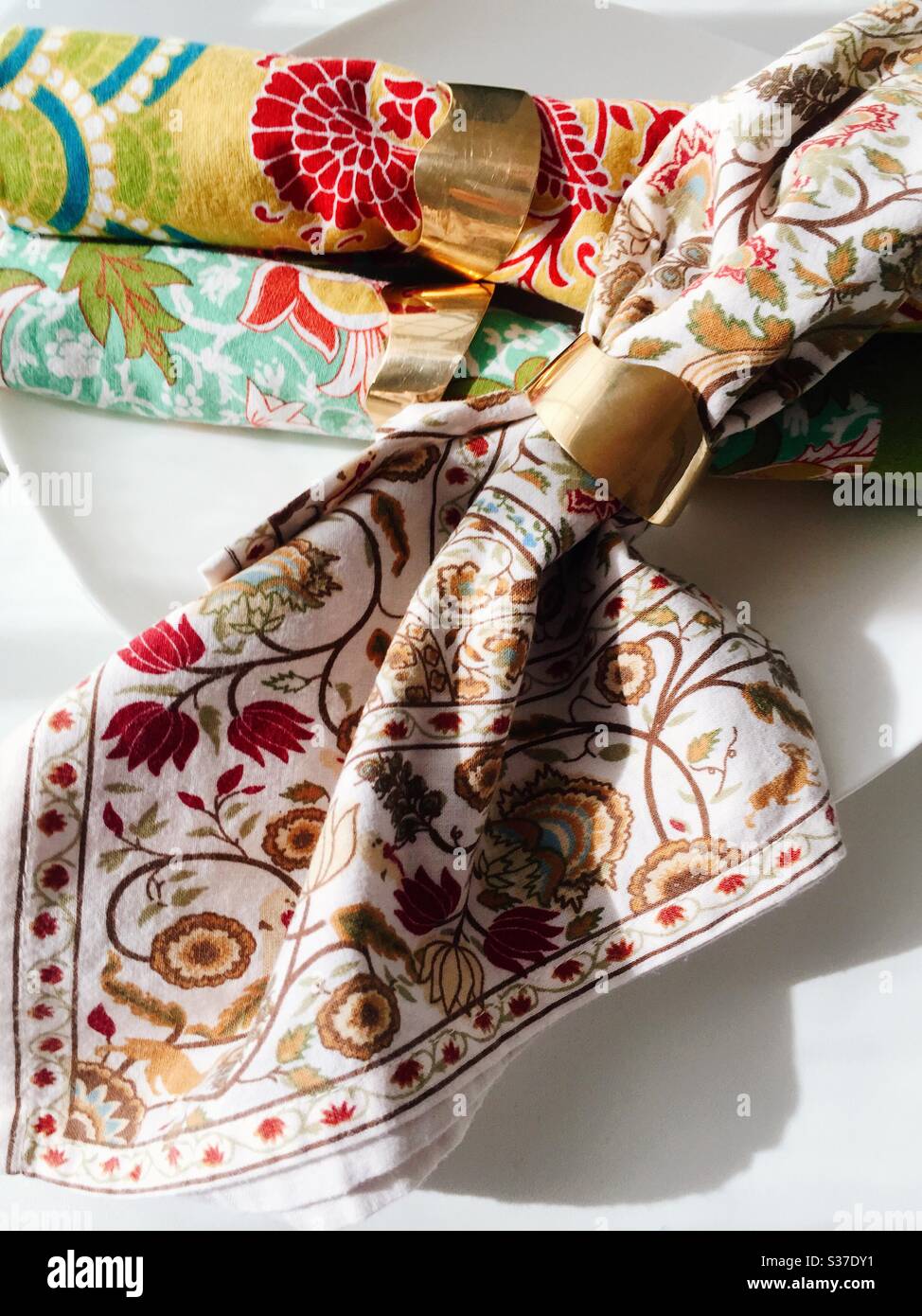 Brass napkin rings make shiny table decoration as they secure brightly colored napkins - Smartphone Captured Stock Image