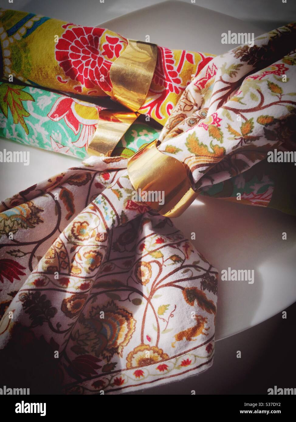 Brass napkin rings securing brightly patterned napkins - Smartphone Captured Stock Image