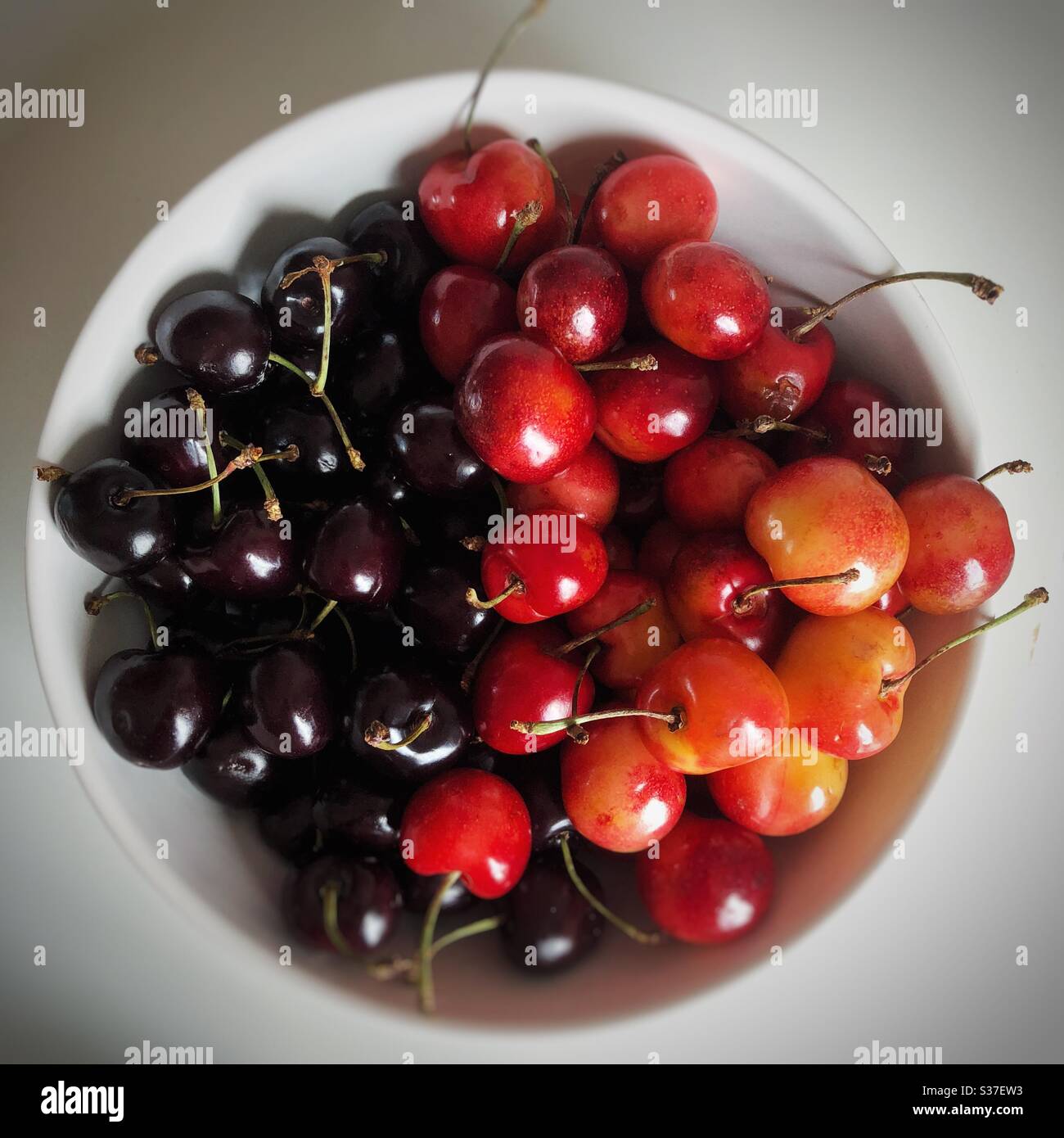 Different types of sweet cherries in white bowl Stock Photo
