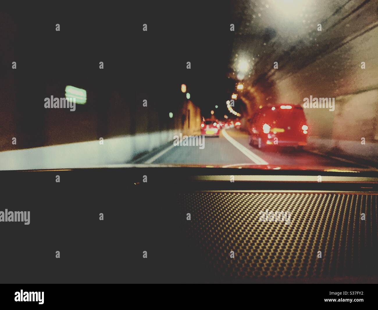 Cars driving through the Tyne Tunnel in North East England. Blurry red brake lights are seen through the windshield. Transport infrastructure. - Smartphone Captured Stock Image