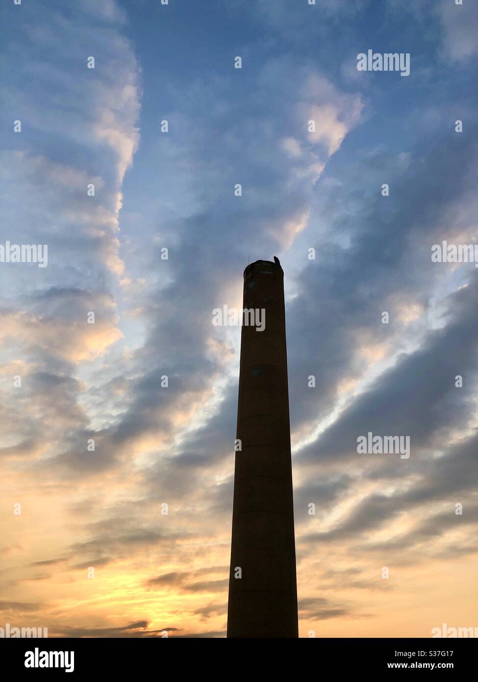Tall chimney against a rising sun - Smartphone Captured Stock Image