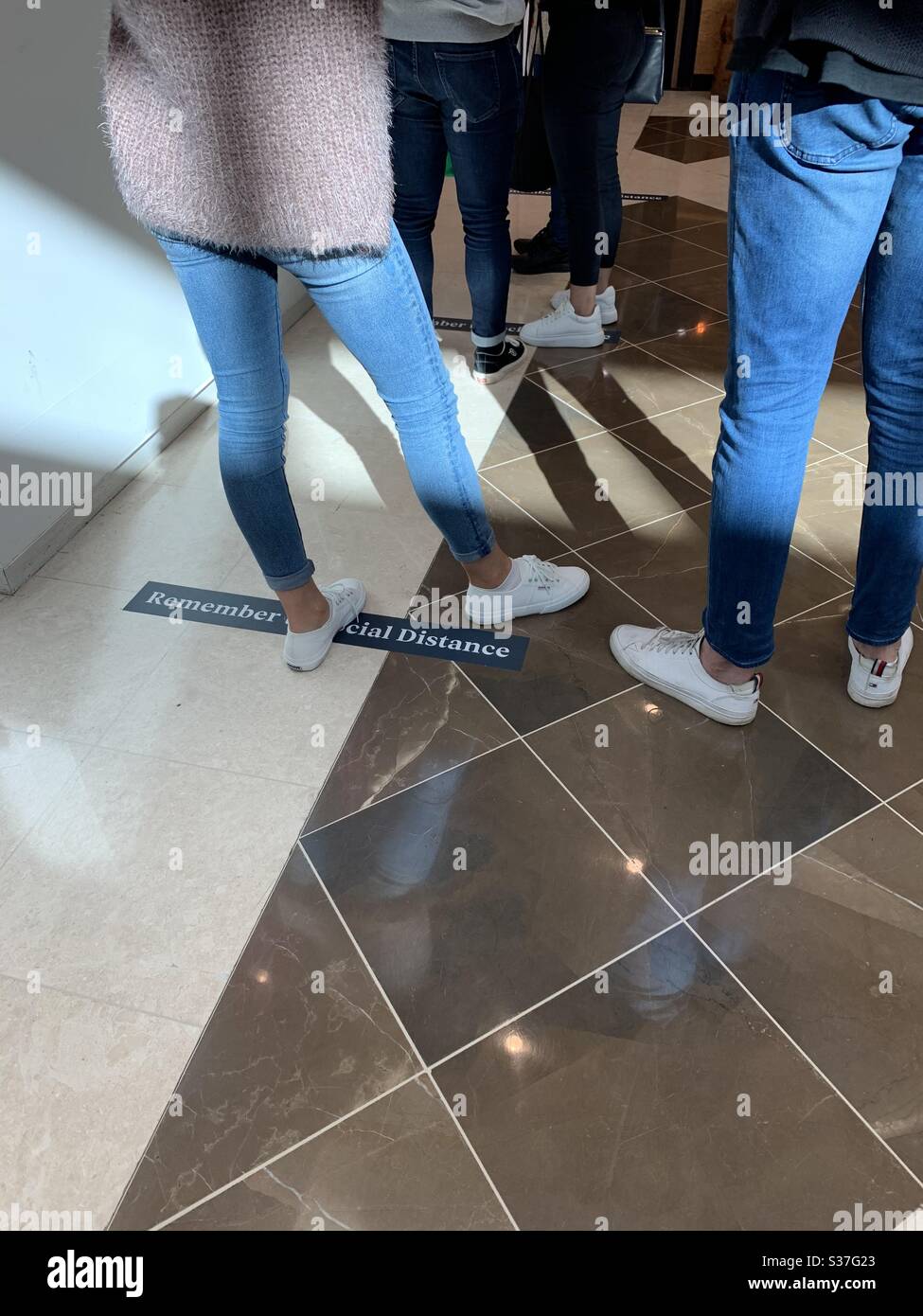 The new normal with people queuing to enter a Uniclo store in Australia - Smartphone Captured Stock Image