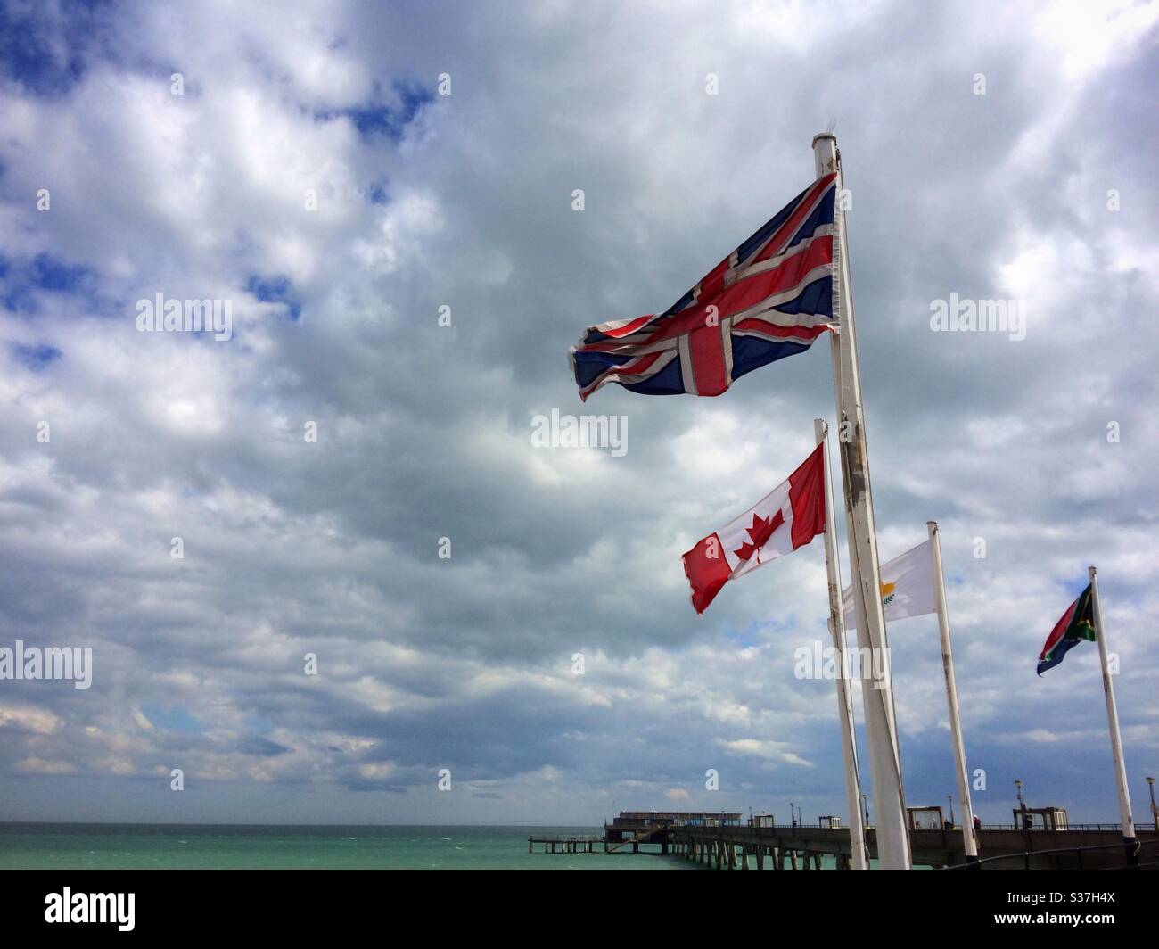 The British Union Jack flag flying next to the Canadian flag at the entry to the pier at Deal Kent UK - Smartphone Captured Stock Image