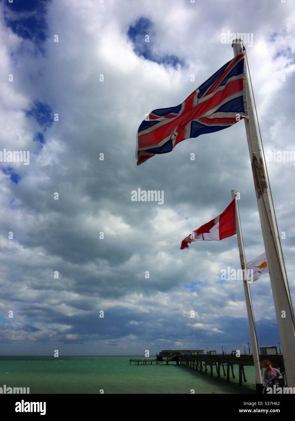 The Union Jack & Canadian flags flying at the entrance to Deal pier in Kent UK - Smartphone Captured Stock Image
