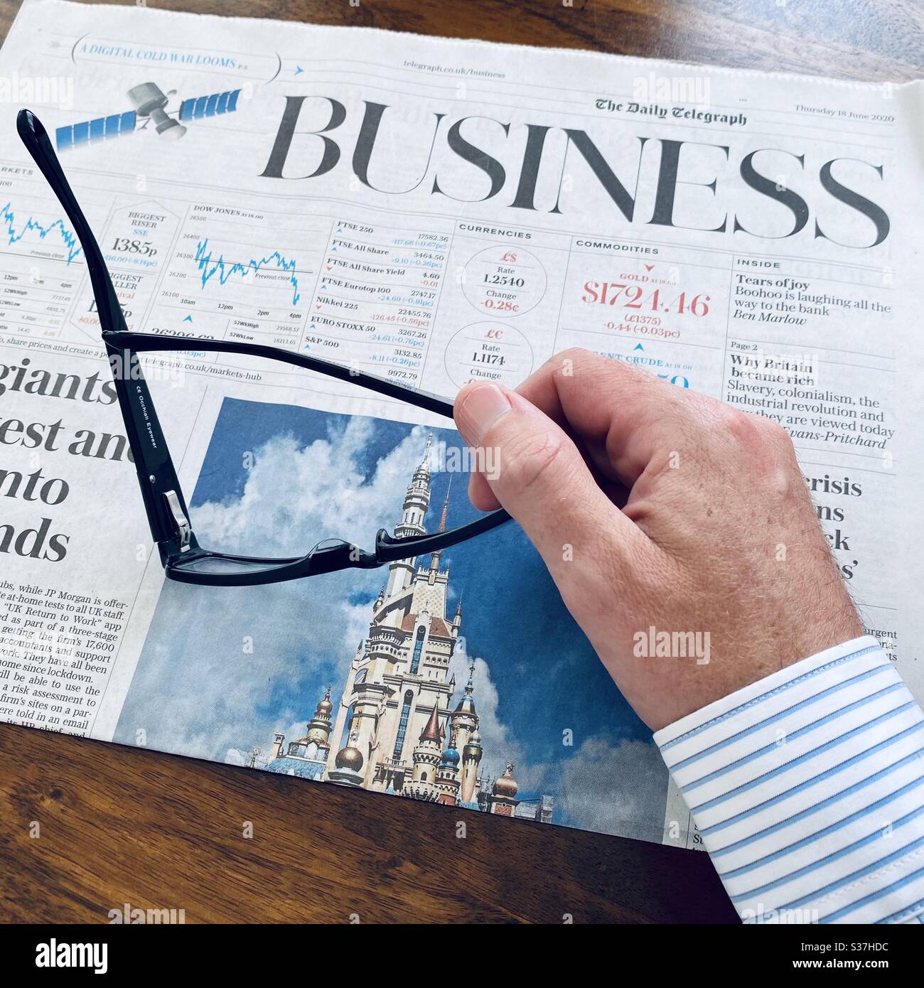 Business and finance concept. Closeup view market trader catching up on financial news with morning coffee, tablet device and business newspaper. FTSE 100 markets in decline during coronavirus crisis - Smartphone Captured Stock Image