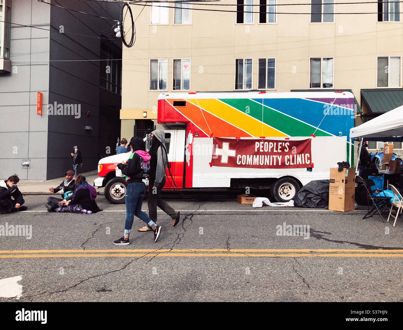 Ambulance vehicle painted rainbow with sign People’s Community Clinic on 12th street in CHAZ CHOP autonomous zone on Capitol hill in Seattle, June 2020 Stock Photo