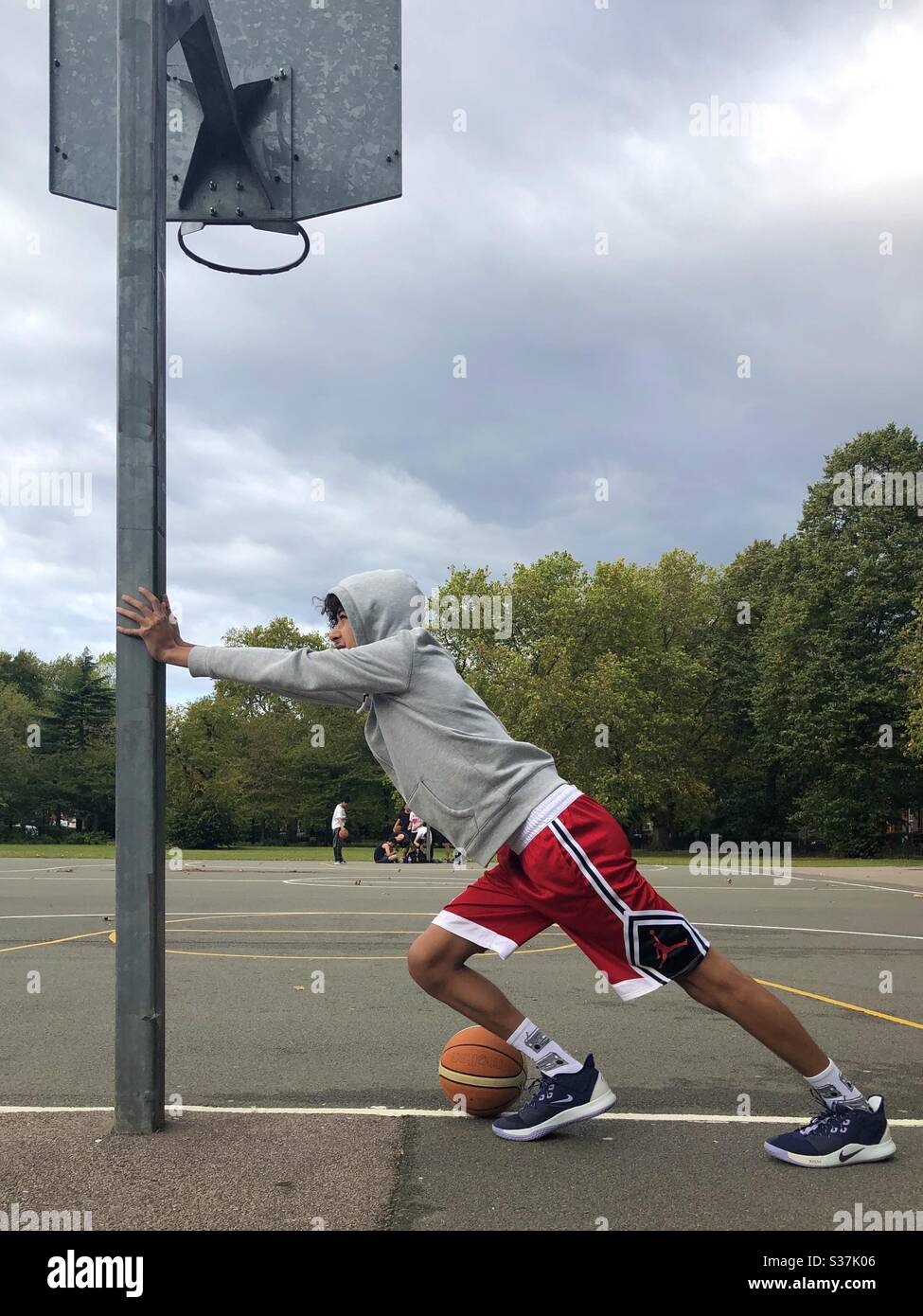 Young guy 19 year old teenager, youth warming up to play basketball, on a court in London, England. Stock Photo