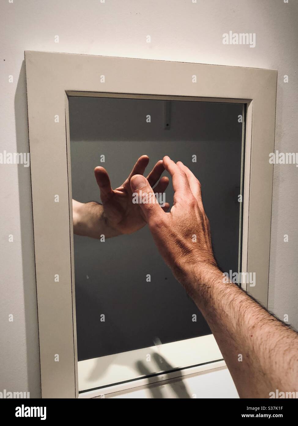 Hand raised up and touching mirror on wall Stock Photo Alamy