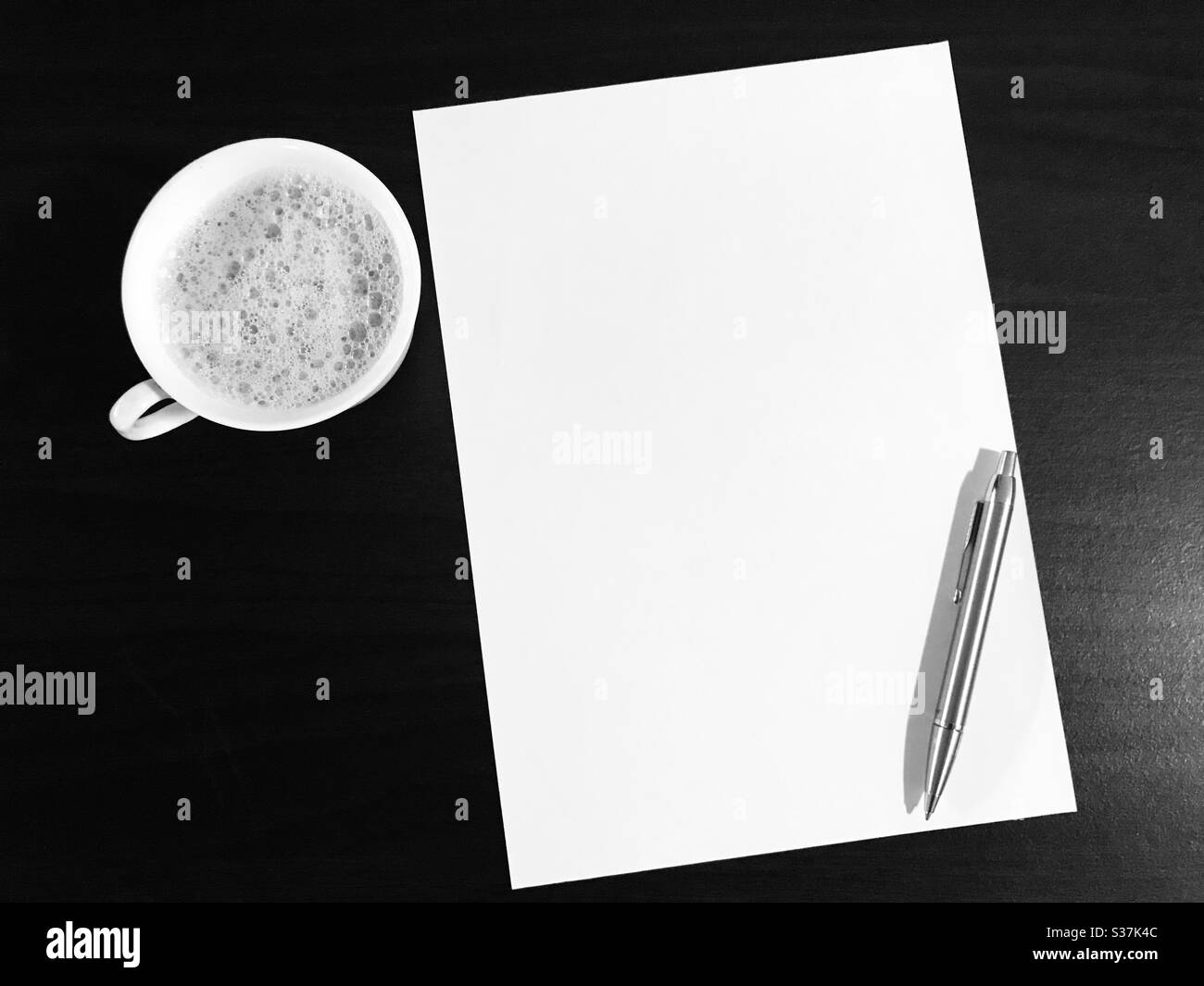 Blank empty paper sheet with a silver coloured pen & cup of Tea beside in black & white mode - empty page ,copy space for your own text “words are unlimited, use it wisely” my own quote Stock Photo