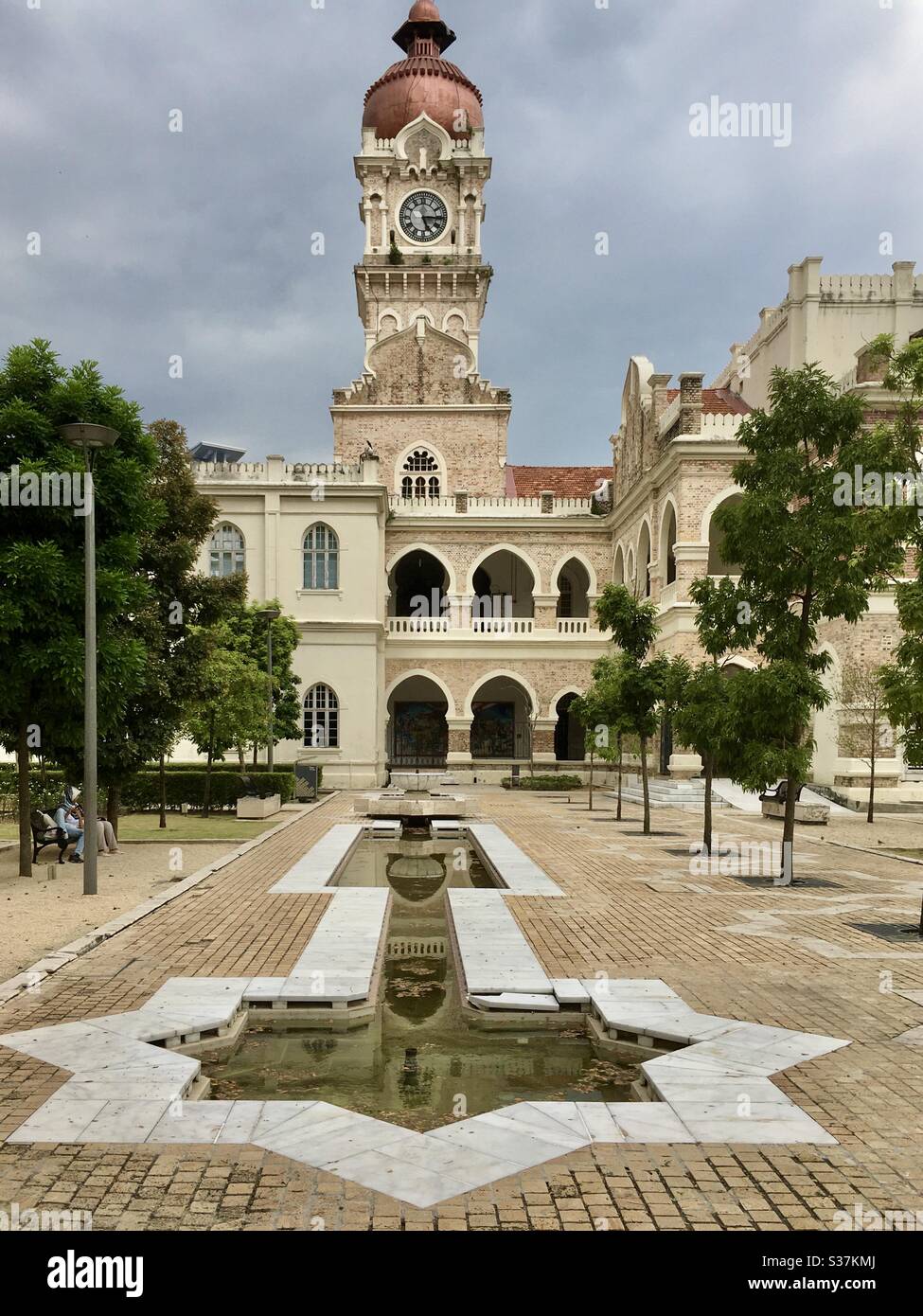 Central clocktower with copper onion dome and pond shaped in Islamic symbol star Rub el Hizb at Sultan Abdul Samad Building Kuala Lumpur Malaysia Stock Photo