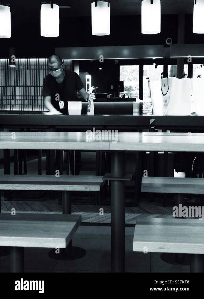 Staff member wipes down surfaces as restaurants offering take away only prepare for reopening on 4th July after coronavirus lockdown in England. - Smartphone Captured Stock Image