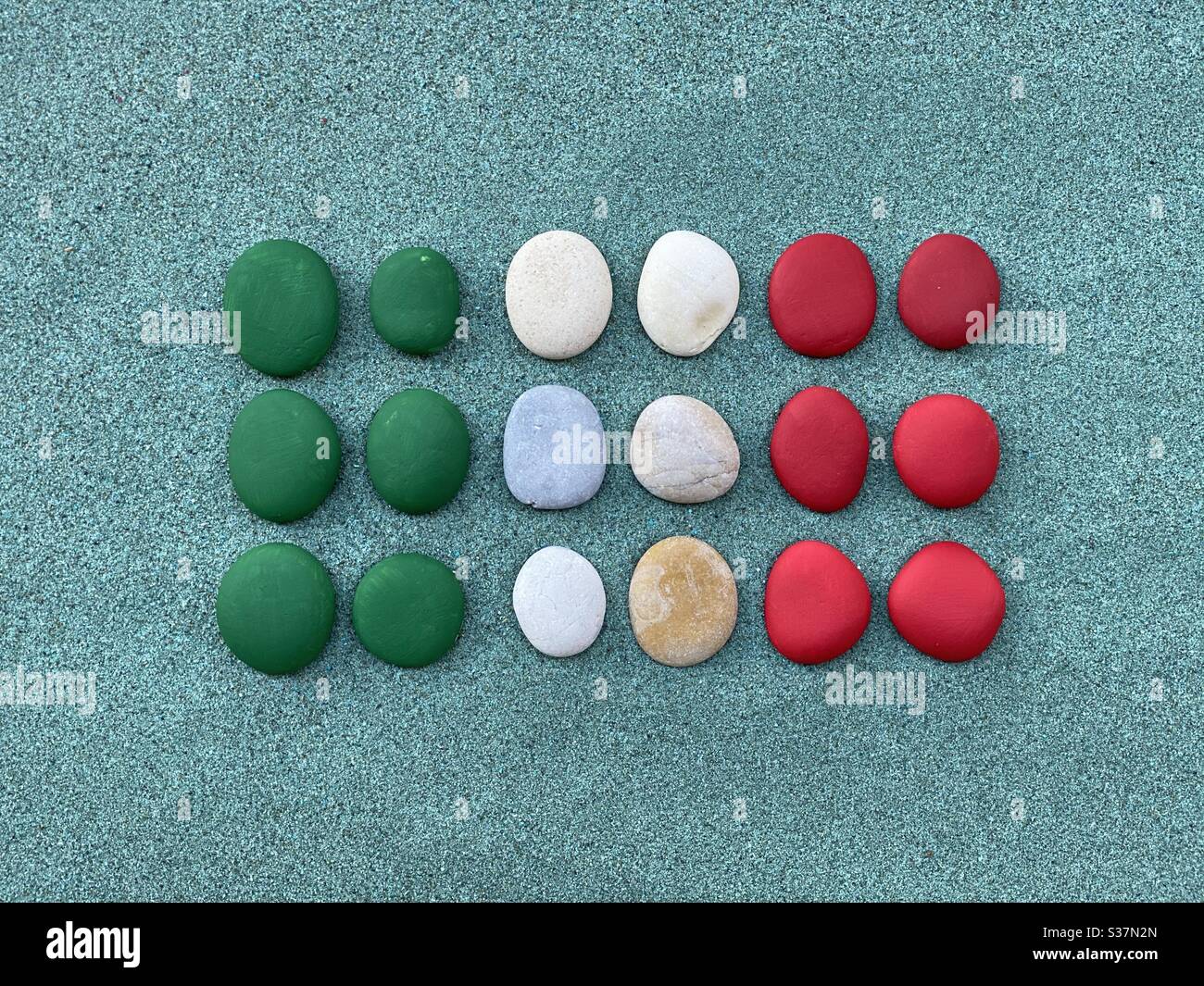 Italian flag composed with colored pebbles over green sand - Smartphone Captured Stock Image
