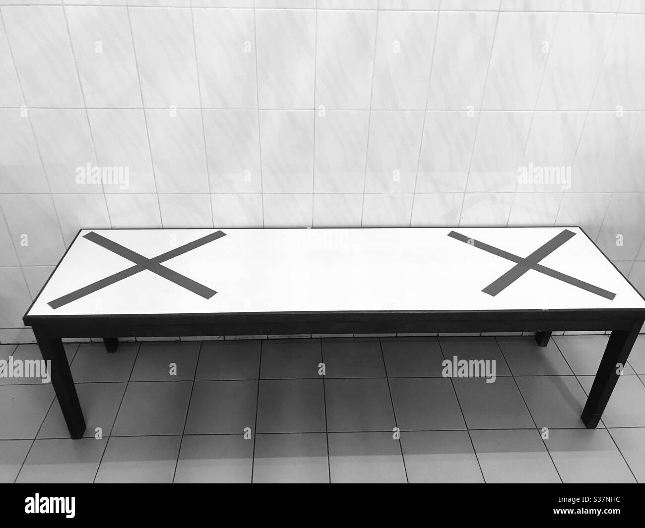 Safe distancing measures have been implemented in order to reduce the spread of the coronavirus.Singapore-Seating benches  are masked with Red adhesive tape to indicate that people should not sit.b&w Stock Photo