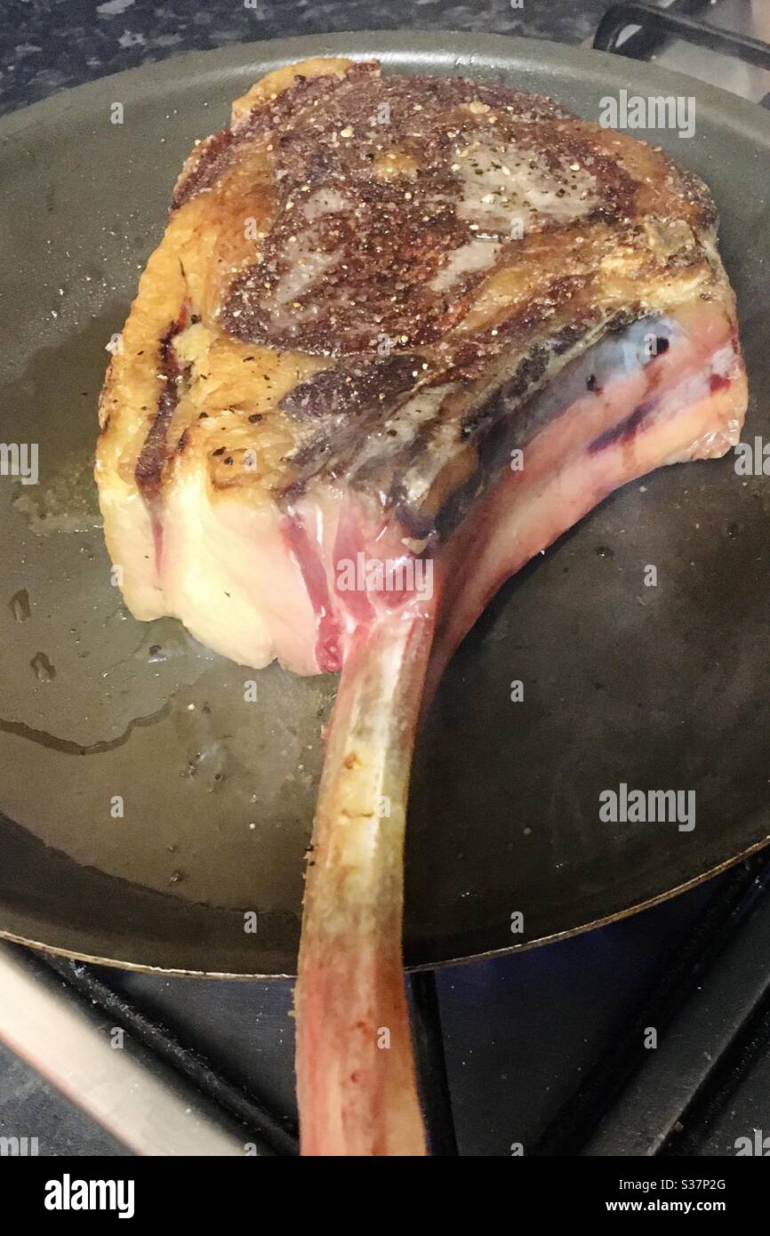 Seasoned Tomahawk steak in a frying pan Stock Photo