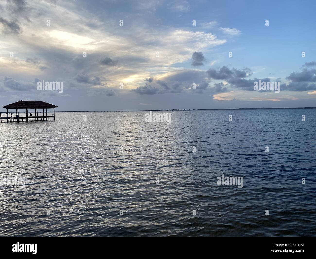 Evening sunset skies over bay water with a fishing pier - Smartphone Captured Stock Image