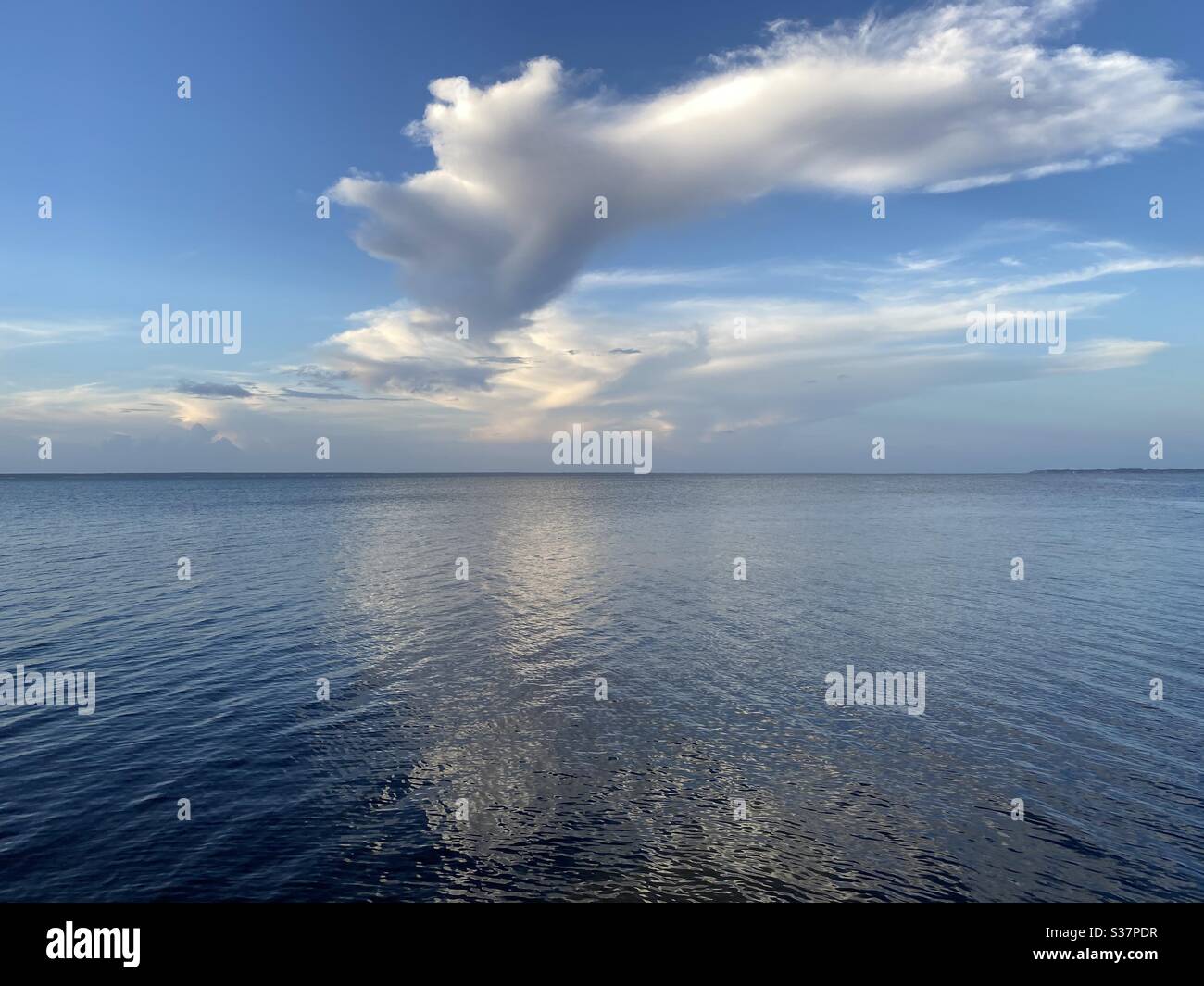 Large cloud formations reflecting onto blue bay water - Smartphone Captured Stock Image