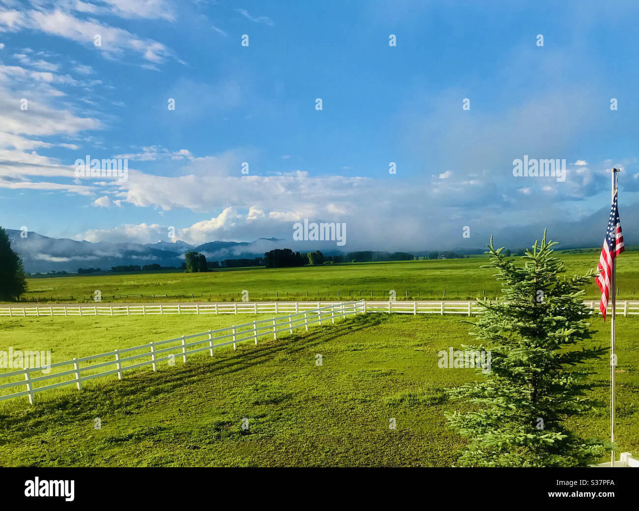 Ranch bordering the grand Teton mountains in Wyoming USA patriotic American flag to the right taken on July 1 three days before July 4 Independence Day - Smartphone Captured Stock Image