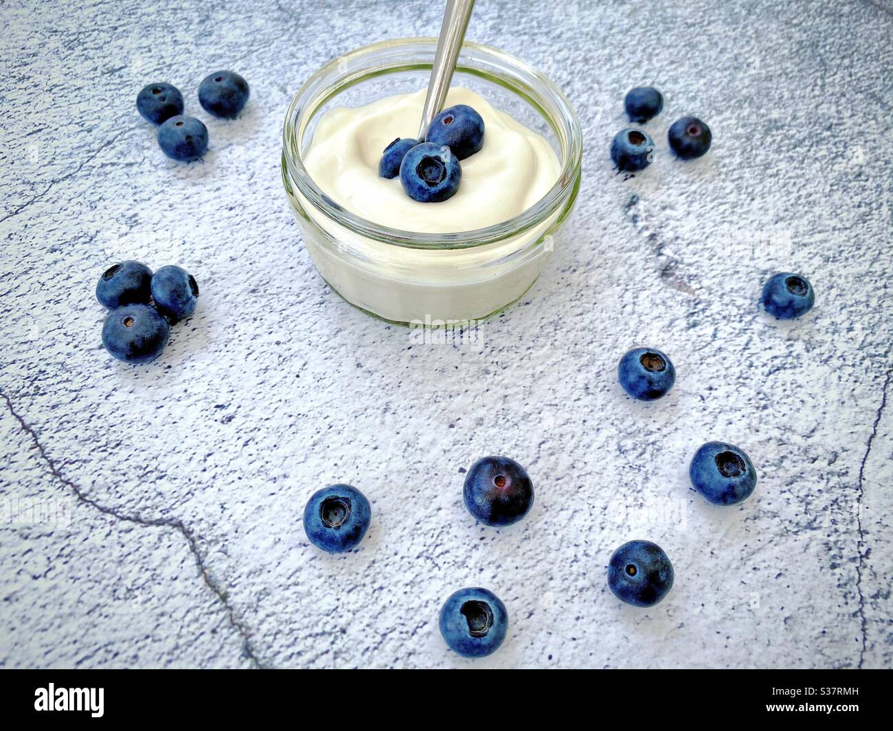 Fresh blueberries and yogurt against a natural stone granite textured background. Healthy summer berries full of antioxidants. Food on the kitchen counter. Stock Photo