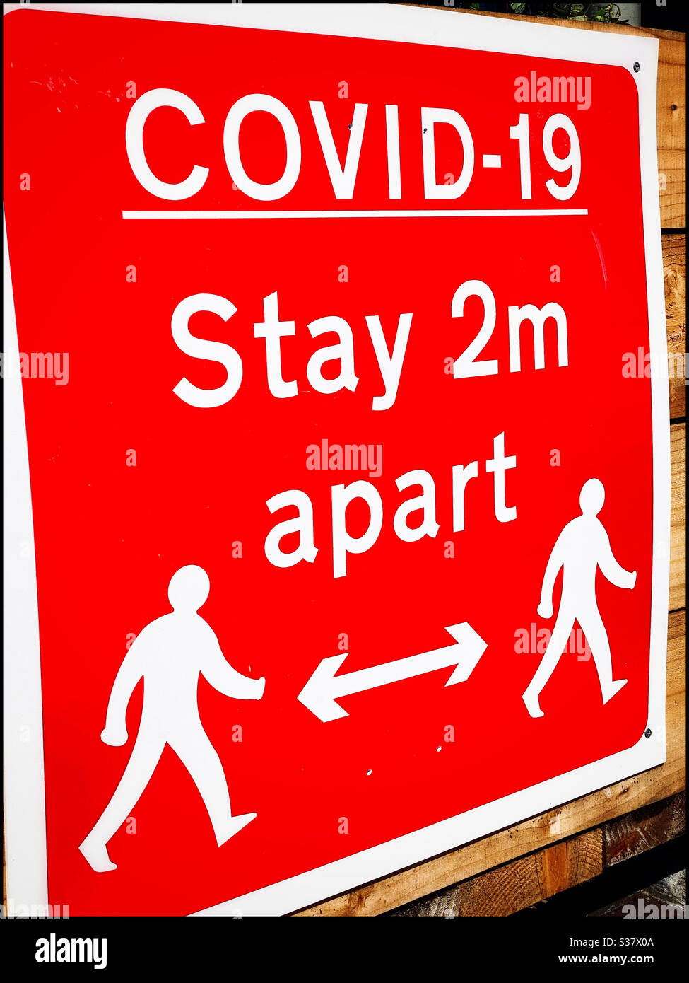WARNING - A bright red sign reminds people that COVID-19 is a real threat and that everyone needs to be at least 2 metres apart. Stay safe. Photo Credit ©️ COLIN HOSKINS. - Smartphone Captured Stock Image