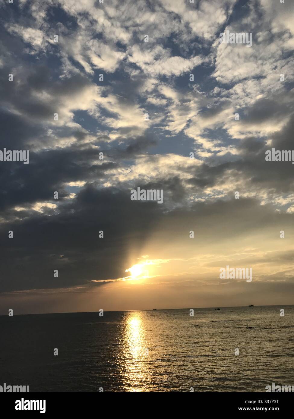 the sun is covered with clouds above the sea Stock Photo