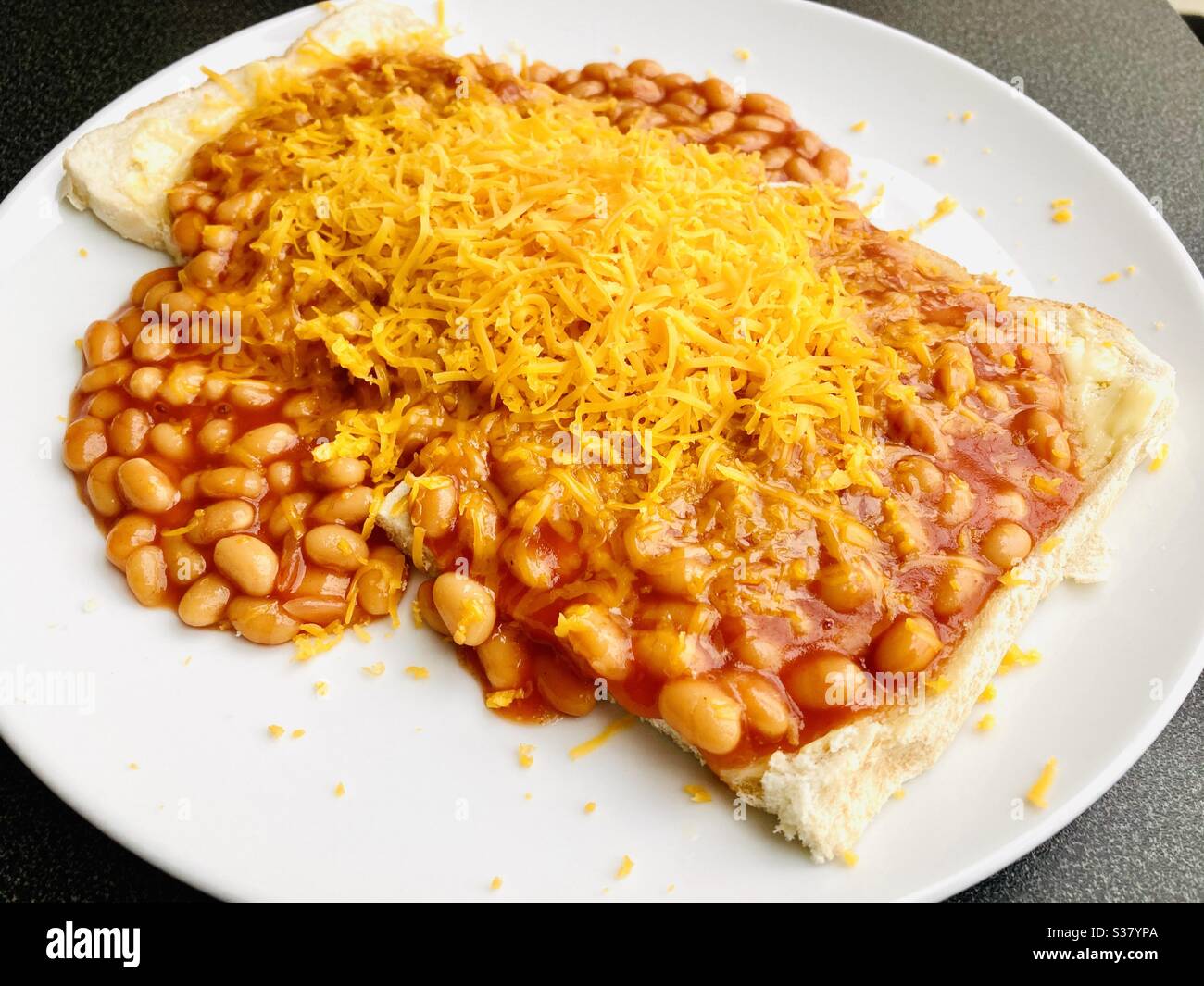 Baked beans served on white toast with grated cheese Stock Photo