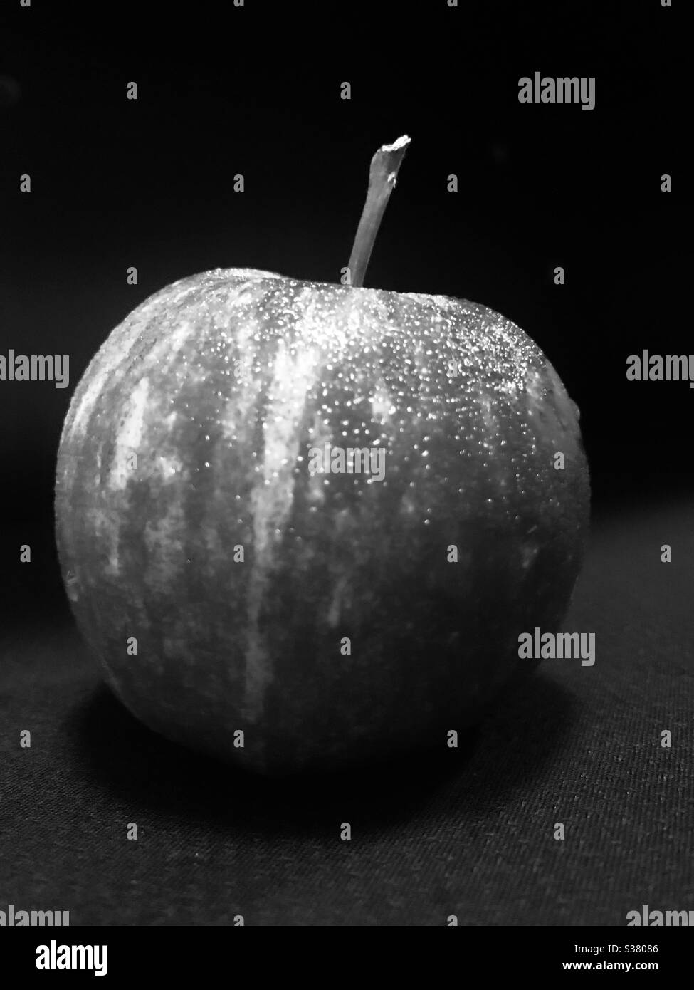 Dramatic black & white look of a red Apple with water droplets after