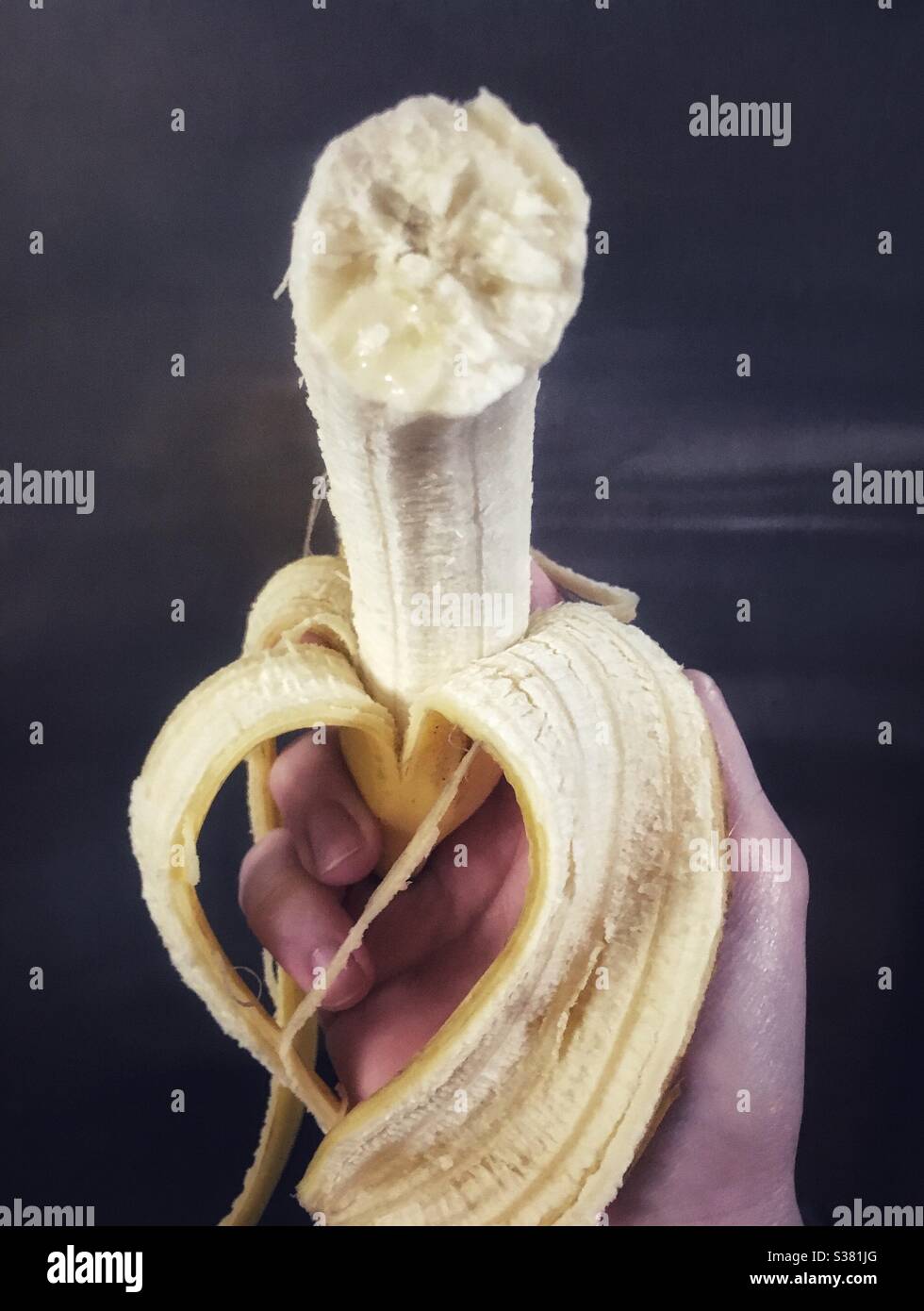 Hand holding partially peeled banana with a bite out of it - Smartphone Captured Stock Image