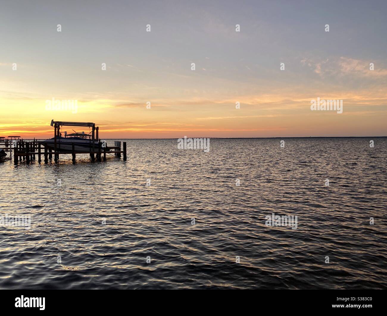 Bright colorful sunset skies over bay water with boat dock Stock Photo ...