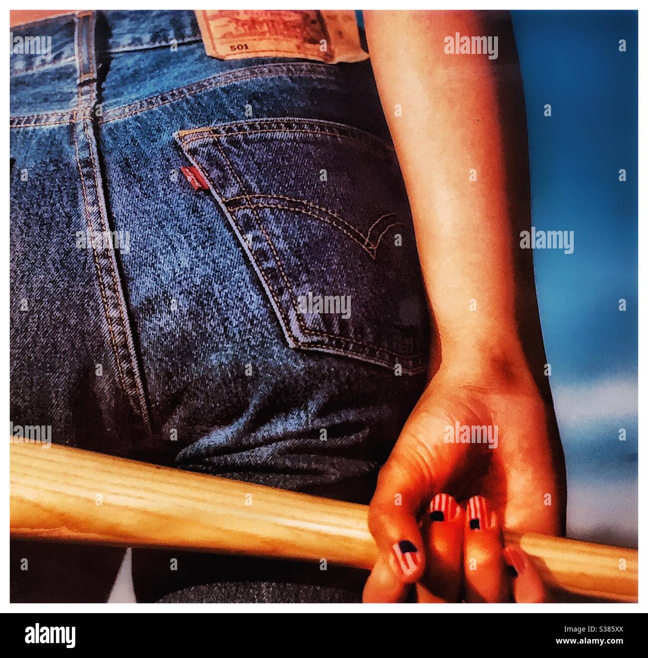 A young woman in jeans grasping a baseball bat. - Smartphone Captured Stock Image