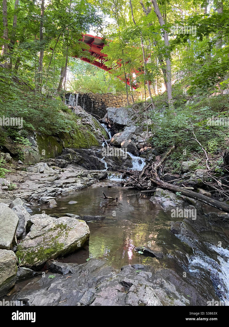 Red bridge over Foundry Brook and waterfall West Point Foundry Preserve Cold Spring New York. Beautiful summer landscape. Stock Photo