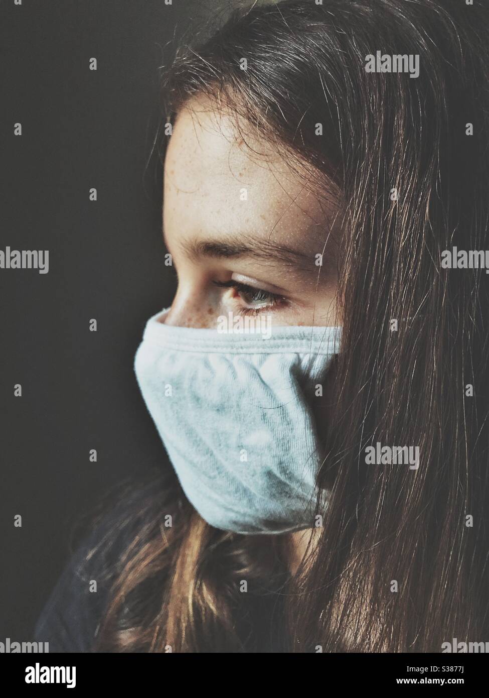 Side view of teenage girl wearing white cotton face mask Stock Photo