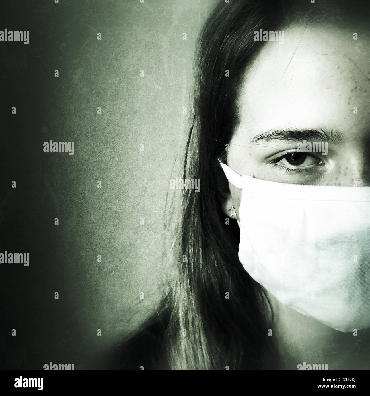 Moody image of teenage girl wearing cotton face mask. Stock Photo