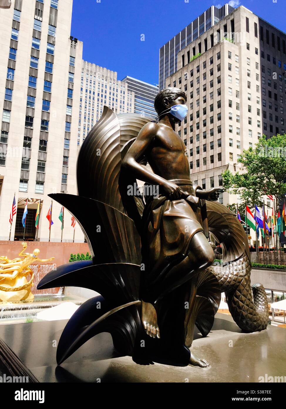The bronze statues of mankind and youth wear face coverings to remind New Yorkers to cover up during the coronavirus pandemic, NYC, USA - Smartphone Captured Stock Image