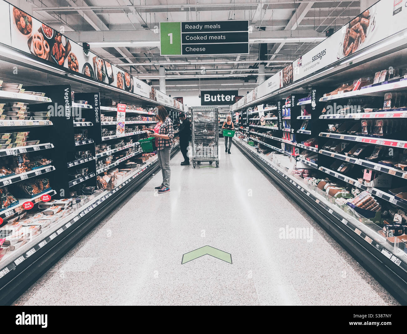 A one way system marked on the floor of a supermarket aisle to promote social distancing due to coronavirus. - Smartphone Captured Stock Image