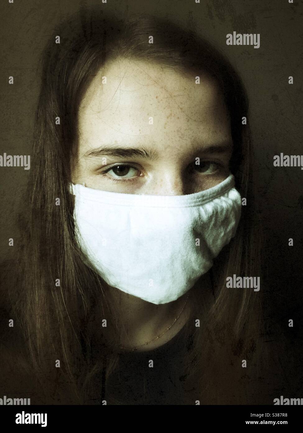 Portrait of teen girl wearing white cotton face mask during Covid-19 pandemic. Stock Photo