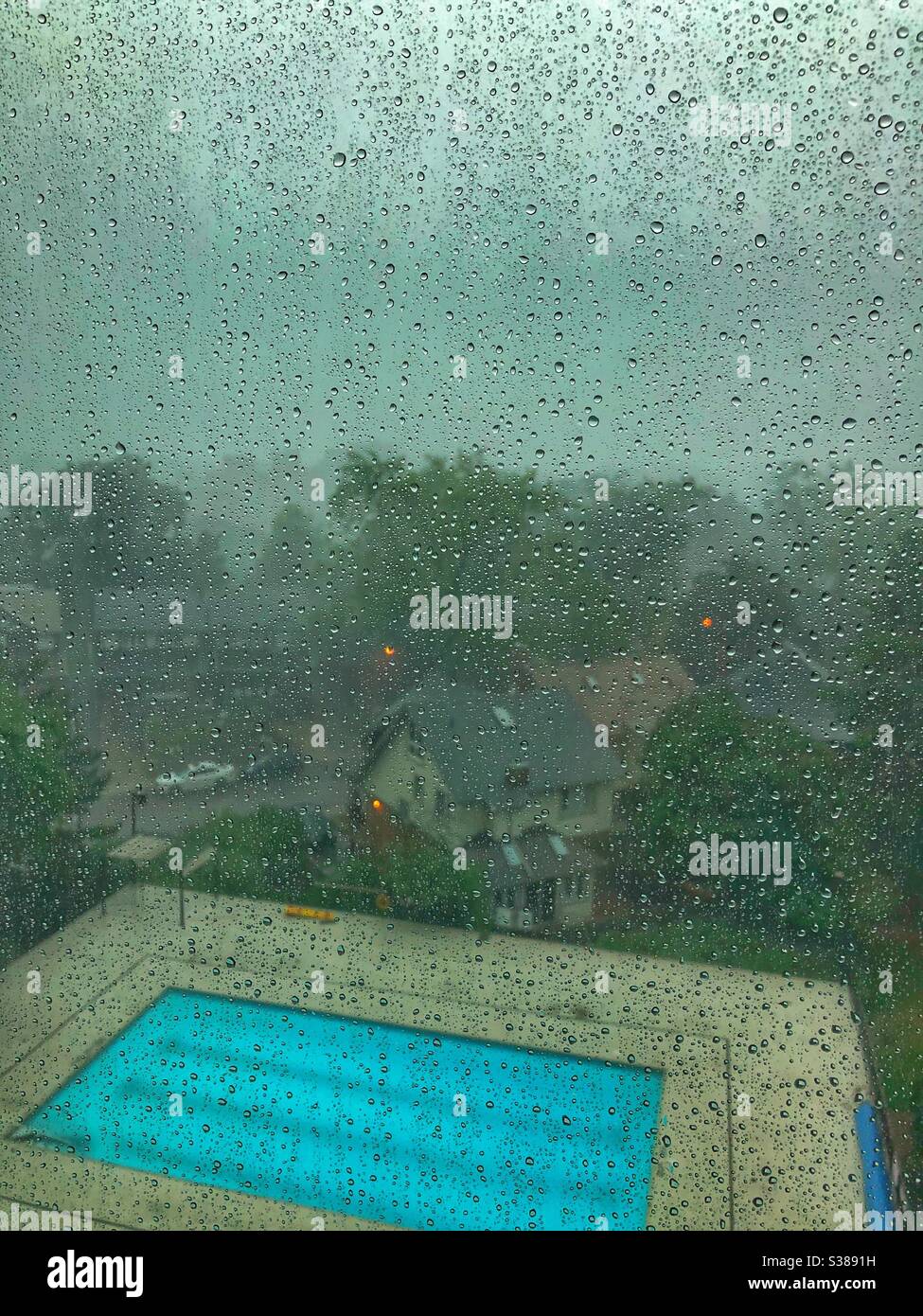 View of an empty pool through a wet window. - Smartphone Captured Stock Image