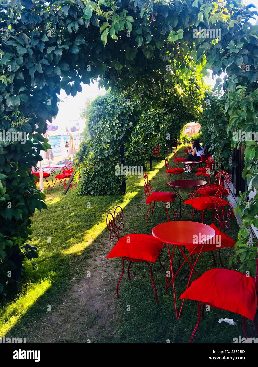A green and red designed cafe in Trogir, Croatia. A yellow stripe of  the sun has entered the space Stock Photo