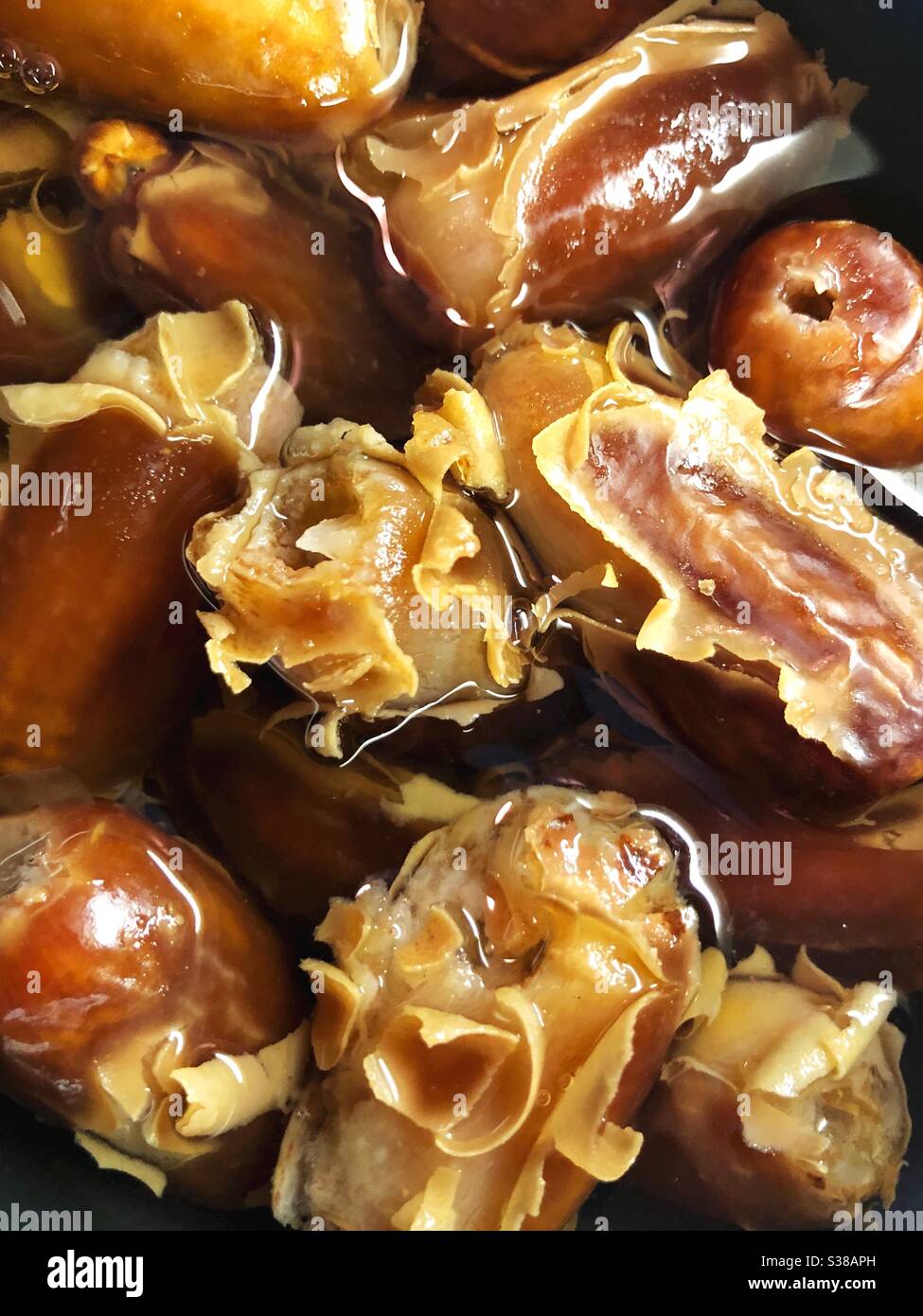 Dates soaking in hot water in preparation to make date syrup. Stock Photo