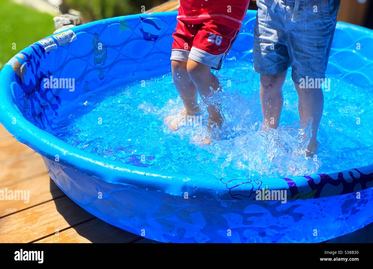 Two kids splashing and playing in the backyard - Smartphone Captured Stock Image