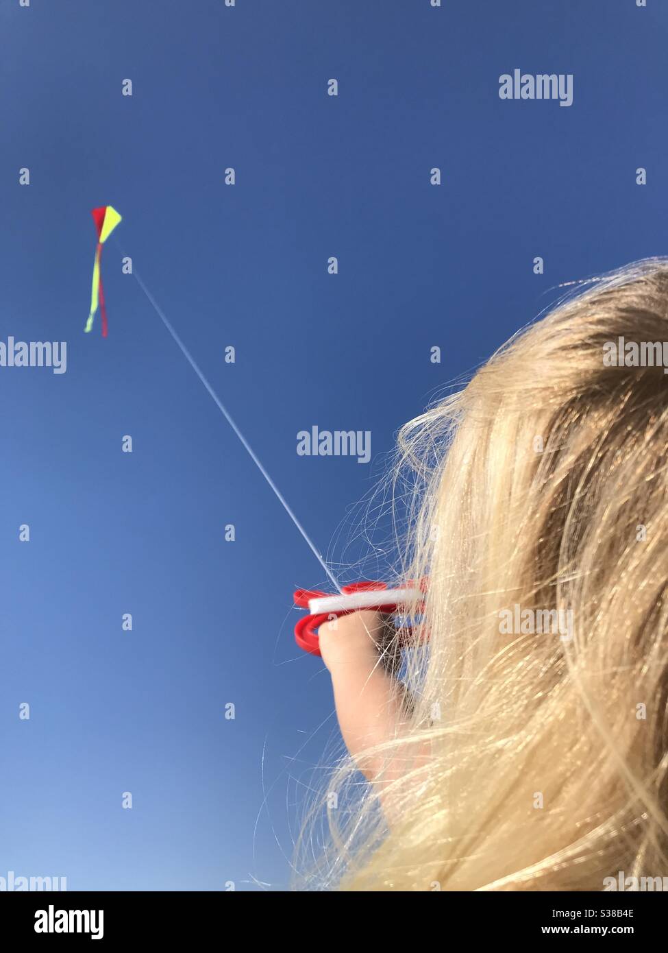 Young blonde girl flying a kite. Stock Photo