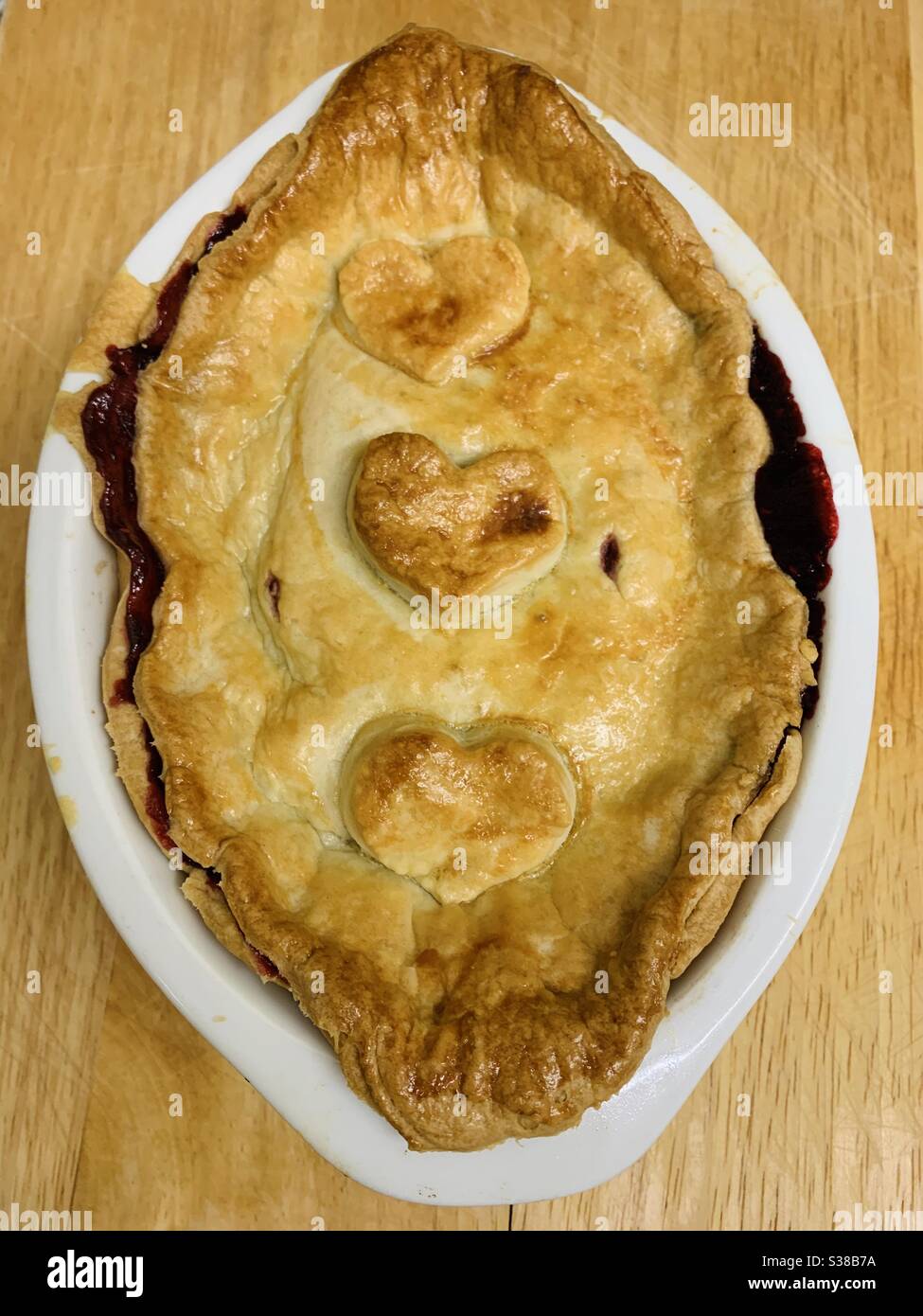 Fruit shortcrust pie on a wooden board in white dish with heart shaped on the front - Smartphone Captured Stock Image