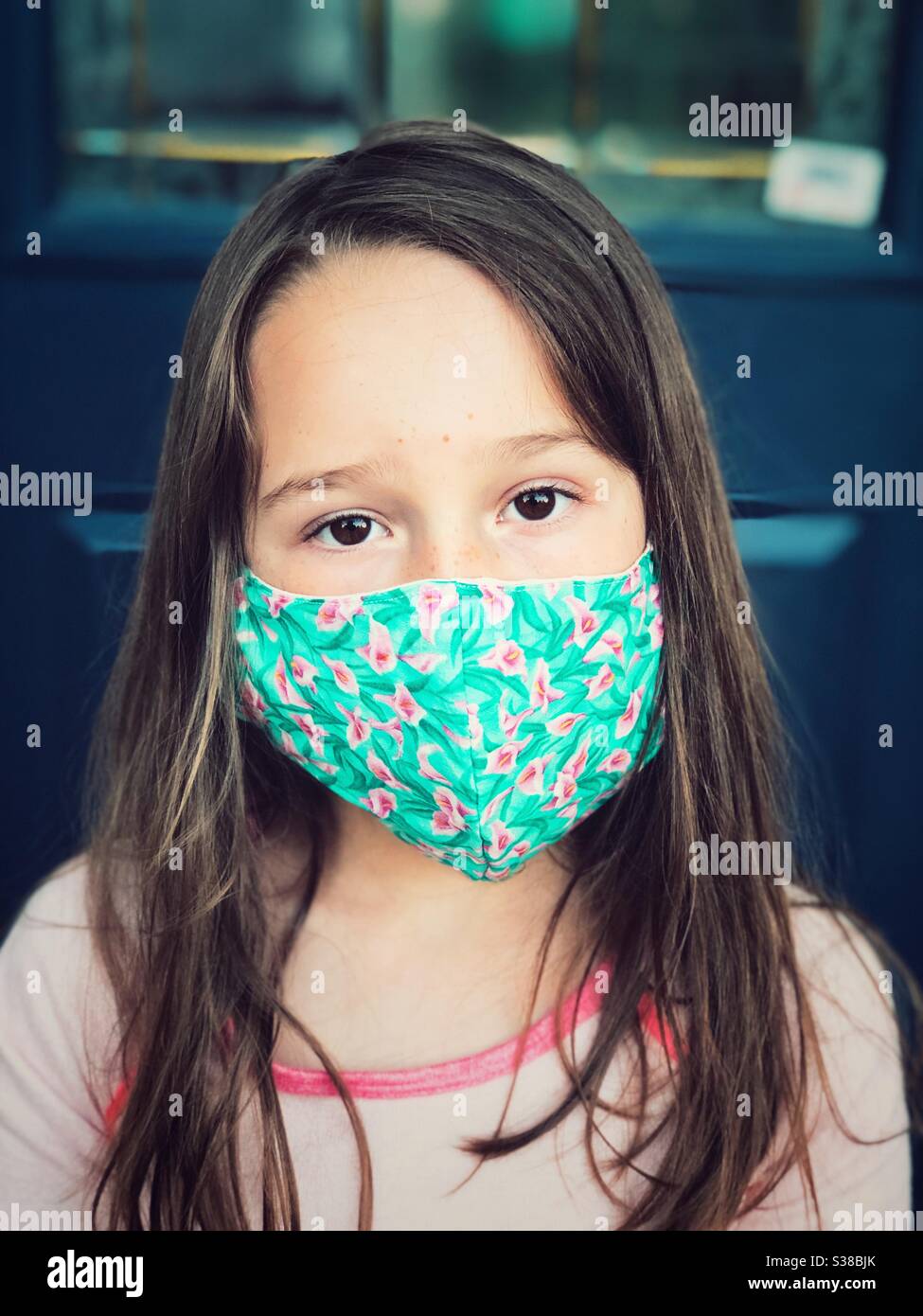 Young girl wearing floral print homemade cotton face mask. Stock Photo