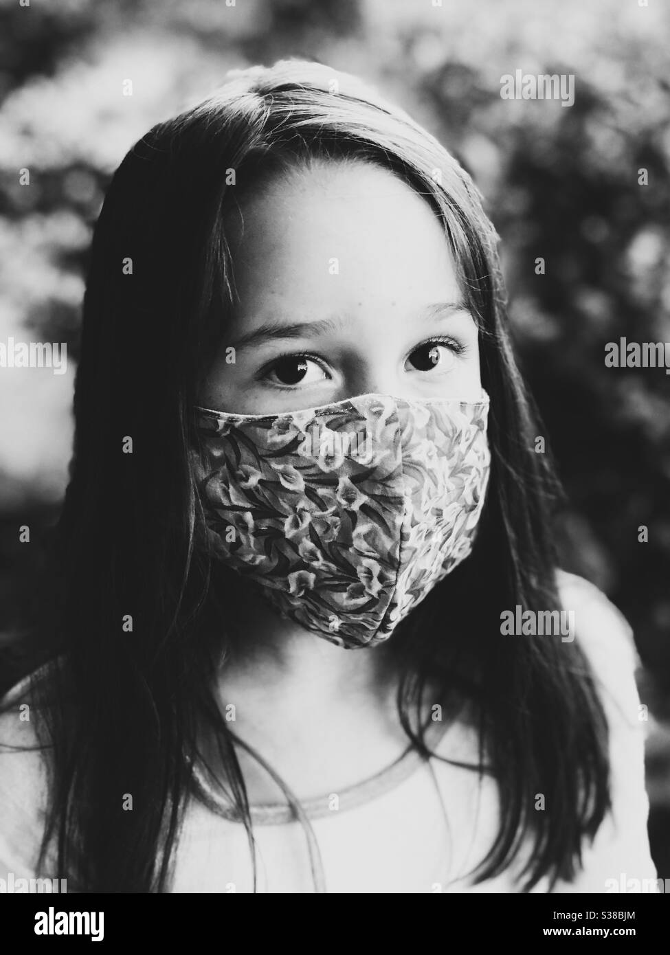 Monochrome image of young girl wearing homemade cotton face mask Stock Photo